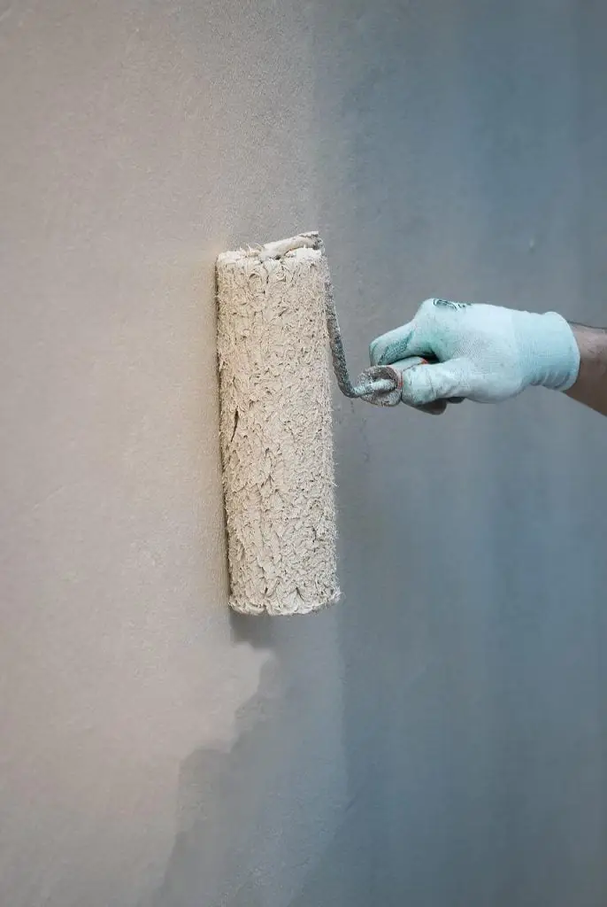 De schilder schildert de muur met witte verf in Enschede