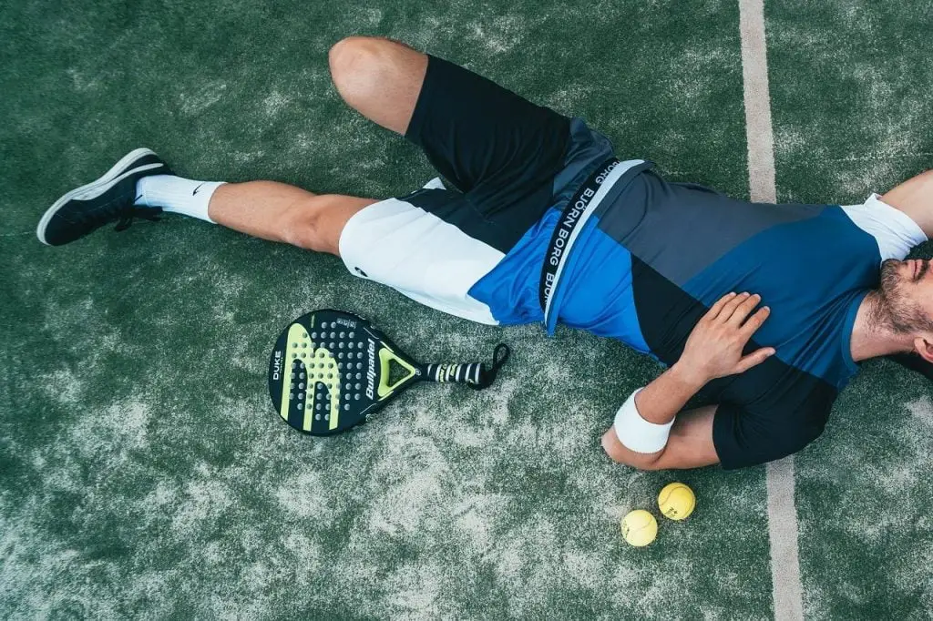 Een man ligt op de tennisbaan. Naast hem werden een tennisracket en een tennisbal geplaatst in Enschede