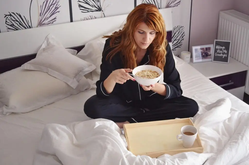 Een vrouw eet ontbijt op haar bed in Enschede