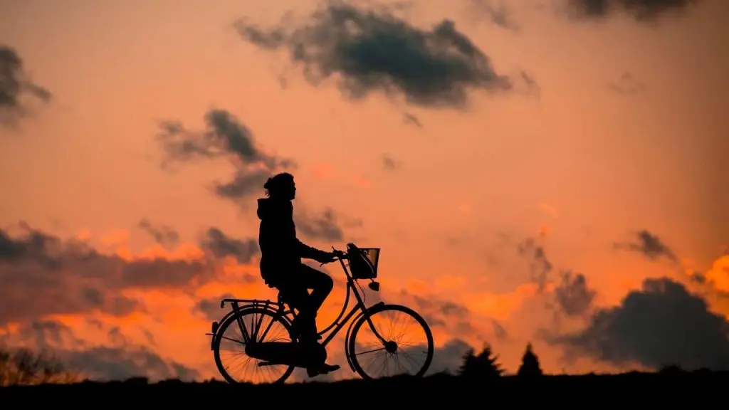Een man fietst bij zonsondergang in Enschede