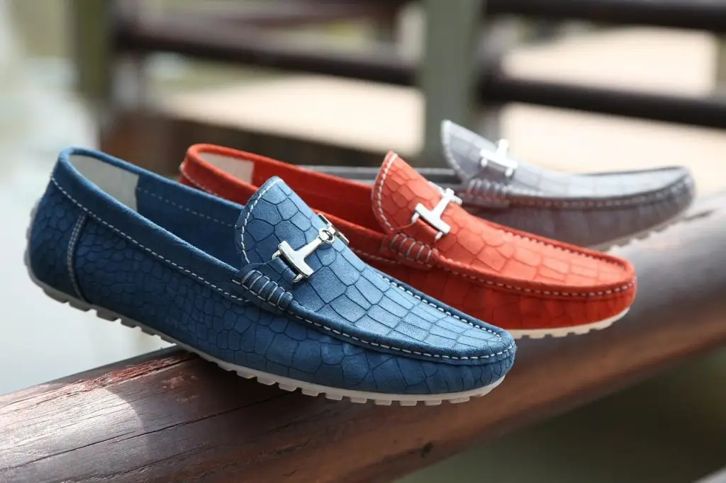 Drie verschillende kleuren herenschoenen op een houten leuning in Enschede
