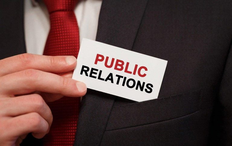 Man in pak houdt visitekaartje vast met 'public relations' erop in Enschede