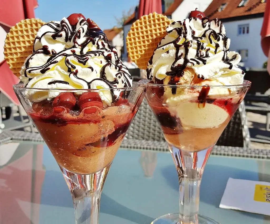 Twee dessertglazen met ijs en toppings, perfect voor een zoete traktatie op een warme dag in Enschede
