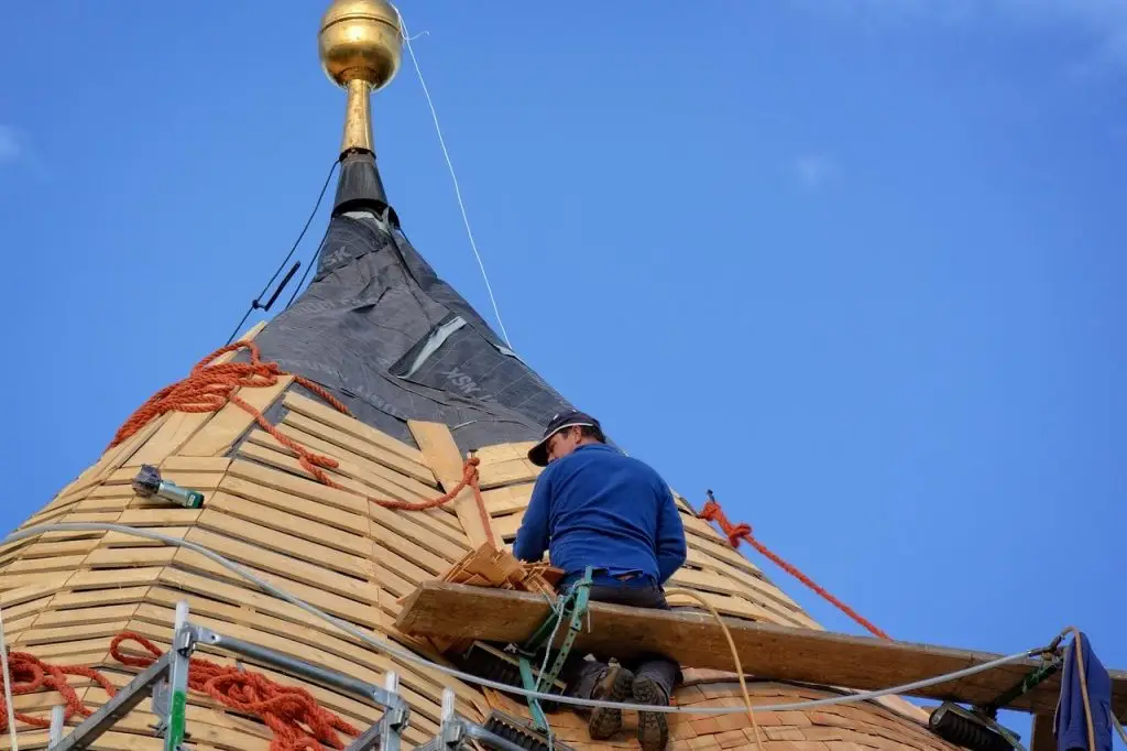 Een dakdekker die aan een houten dak werkt in Enschede