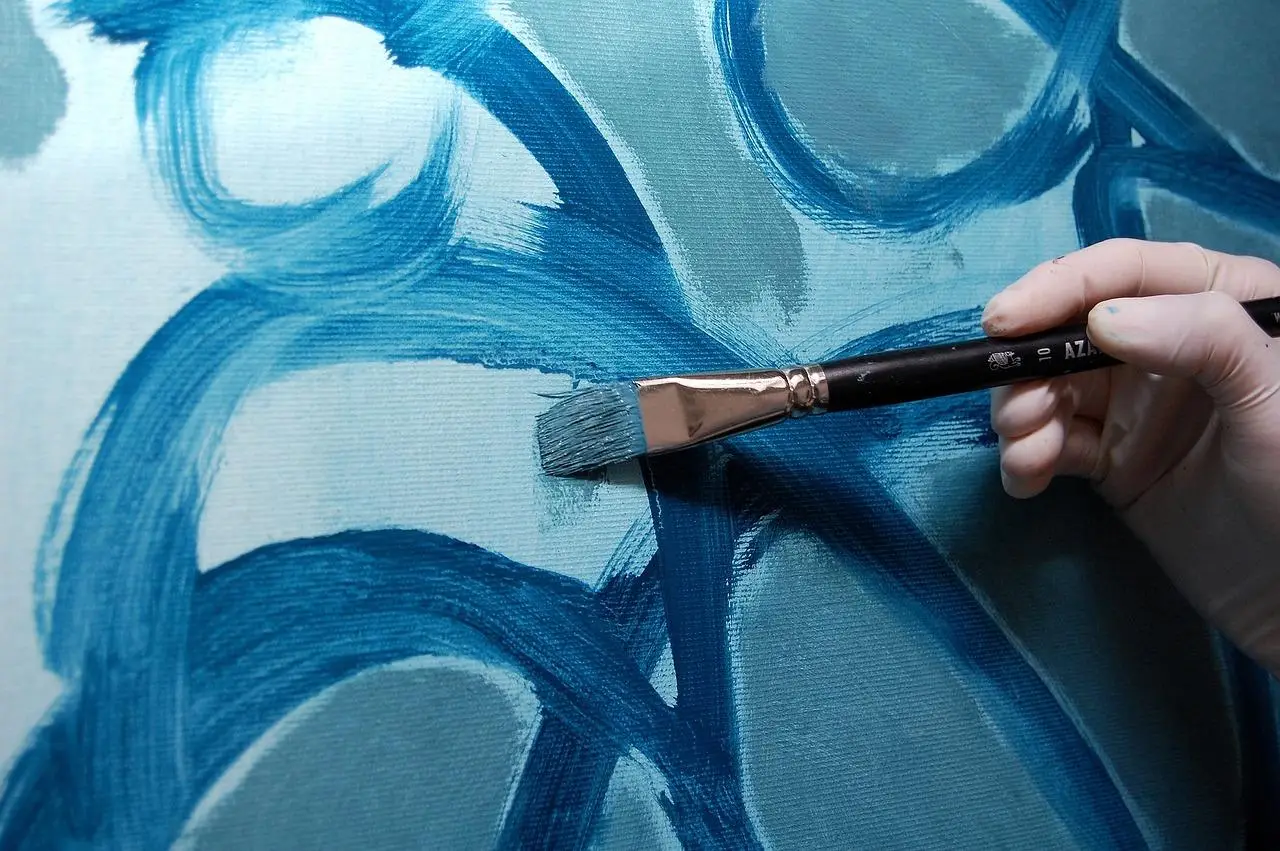 Een persoon die een levendig abstract schilderij maakt met blauwe en witte kleuren, waardoor een vleugje creativiteit aan het canvas wordt toegevoegd in Enschede